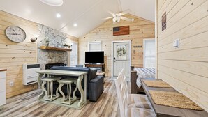 A cozy cabin interior with a dining area, a TV, and a fireplace. - Riverfront Cottage / Fish Camp Getaway (Newland)