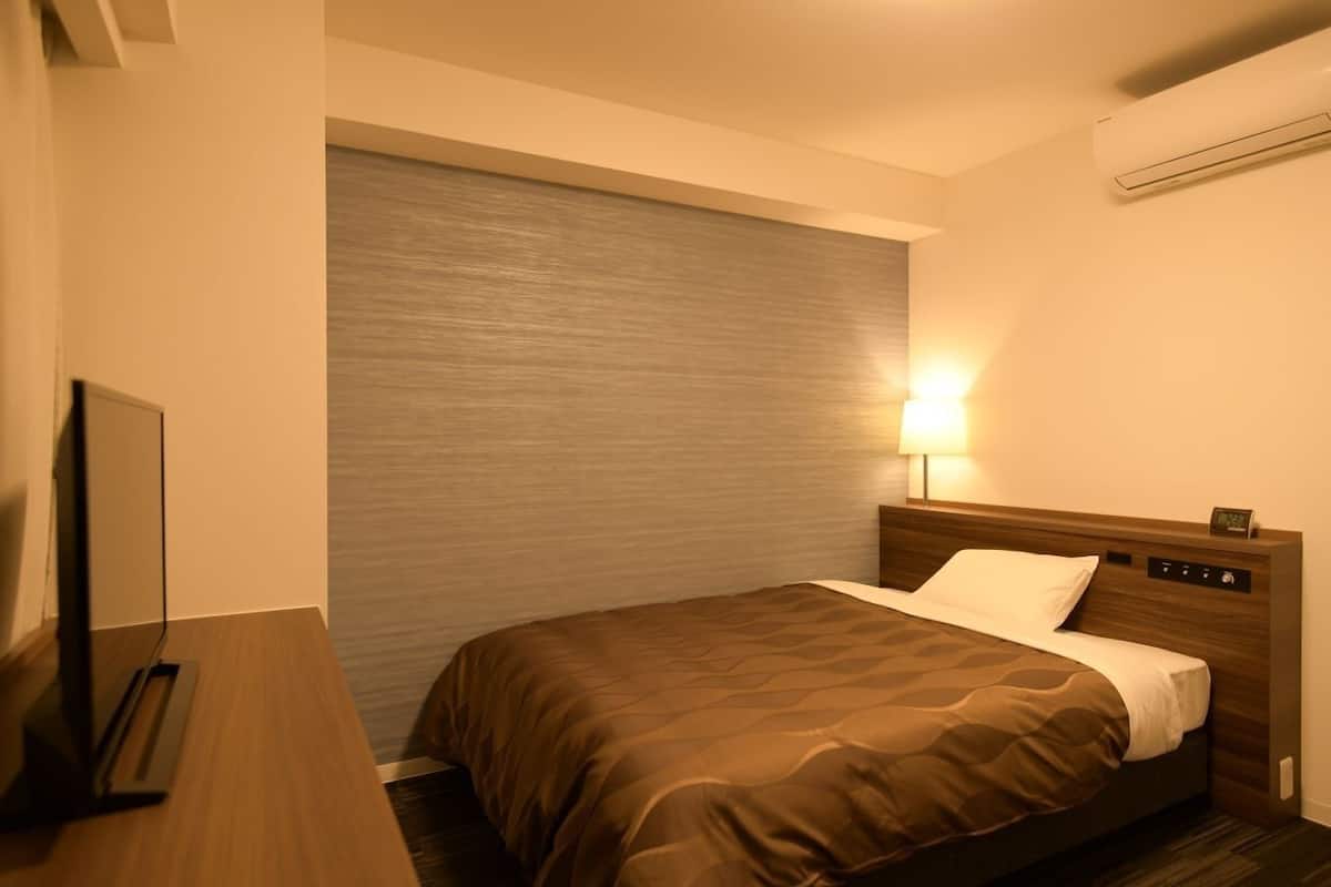 Une chambre d’hôtel équipée d’un lit, d’une lampe de chevet, d’un téléviseur et d’un appareil de climatisation.