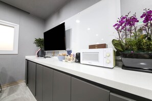A modern kitchen with a flat-screen TV, a radio, and a potted orchid. - City Hotel (Jincheon)