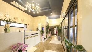 Uma área de recepção de hotel com um balcão, um relógio e um candelabro.