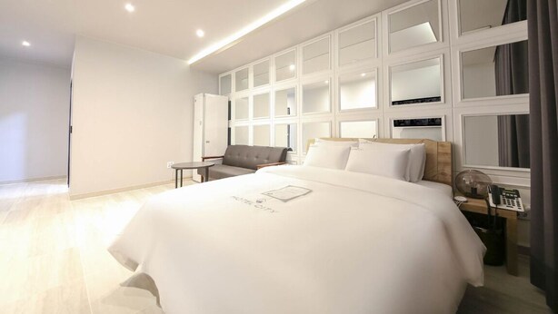 Quarto de hotel moderno com uma cama grande, uma escrivaninha, uma cadeira e um guarda-roupa com espelhos.