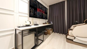 Uma sala de estar moderna com uma grande TV de tela plana na parede exibindo o logotipo da Netflix, um sofá branco elegante, uma mesa de centro pequena e uma poltrona massagem.