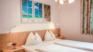 A double bed with a wooden headboard, a bedside table with a lamp, and a wall with three framed pictures.