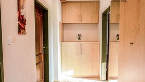 A kitchen with light wood cabinets, a tiled floor, and a small plant on the countertop.