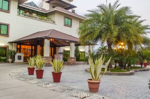 A hotel entrance with a covered patio, potted plants, and a palm tree. - Jalsa Hotel & Banquets (Indore)