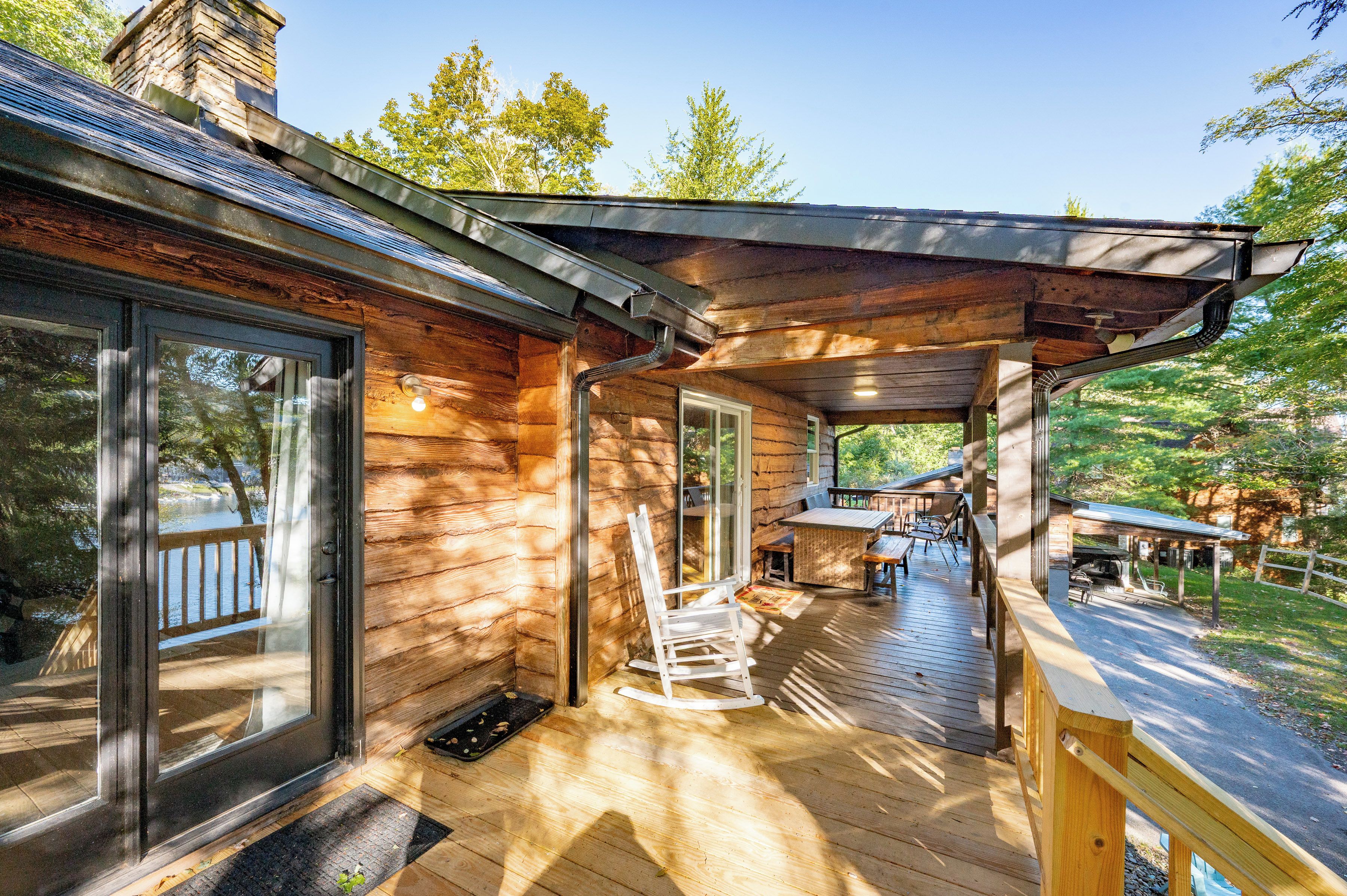 A wooden cabin with a covered porch, large windows, and a deck area.