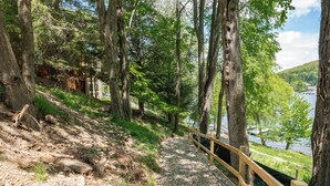 A forested area with a wooden deck and a view of a lake. - Cozy Lakefront Retreat w/ Game Room & Hot Tub (McHenry)