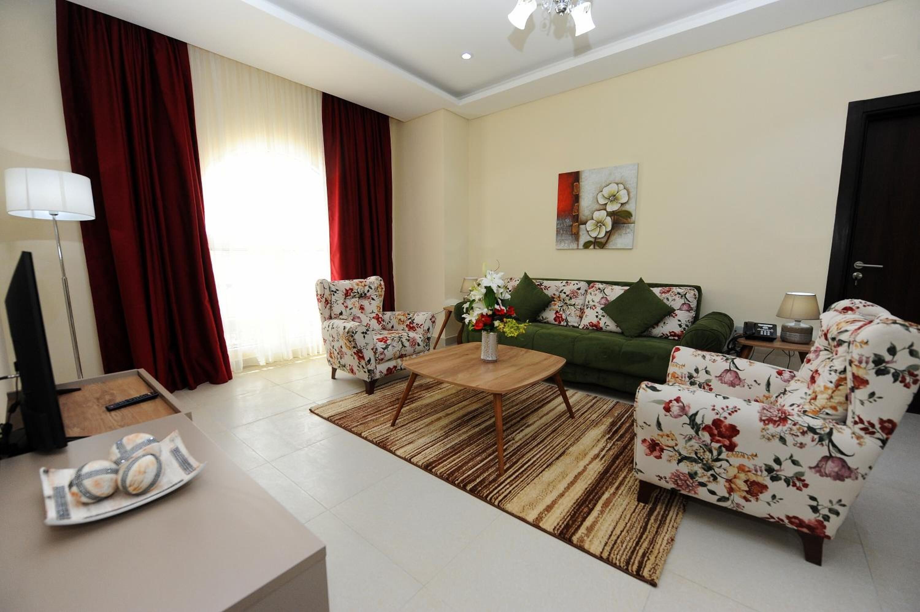 A living room with a sofa, two armchairs, a coffee table, and a TV.