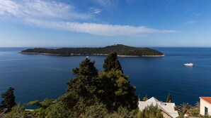 Un paysage côtier avec une petite île, un ciel bleu clair et une mer calme.