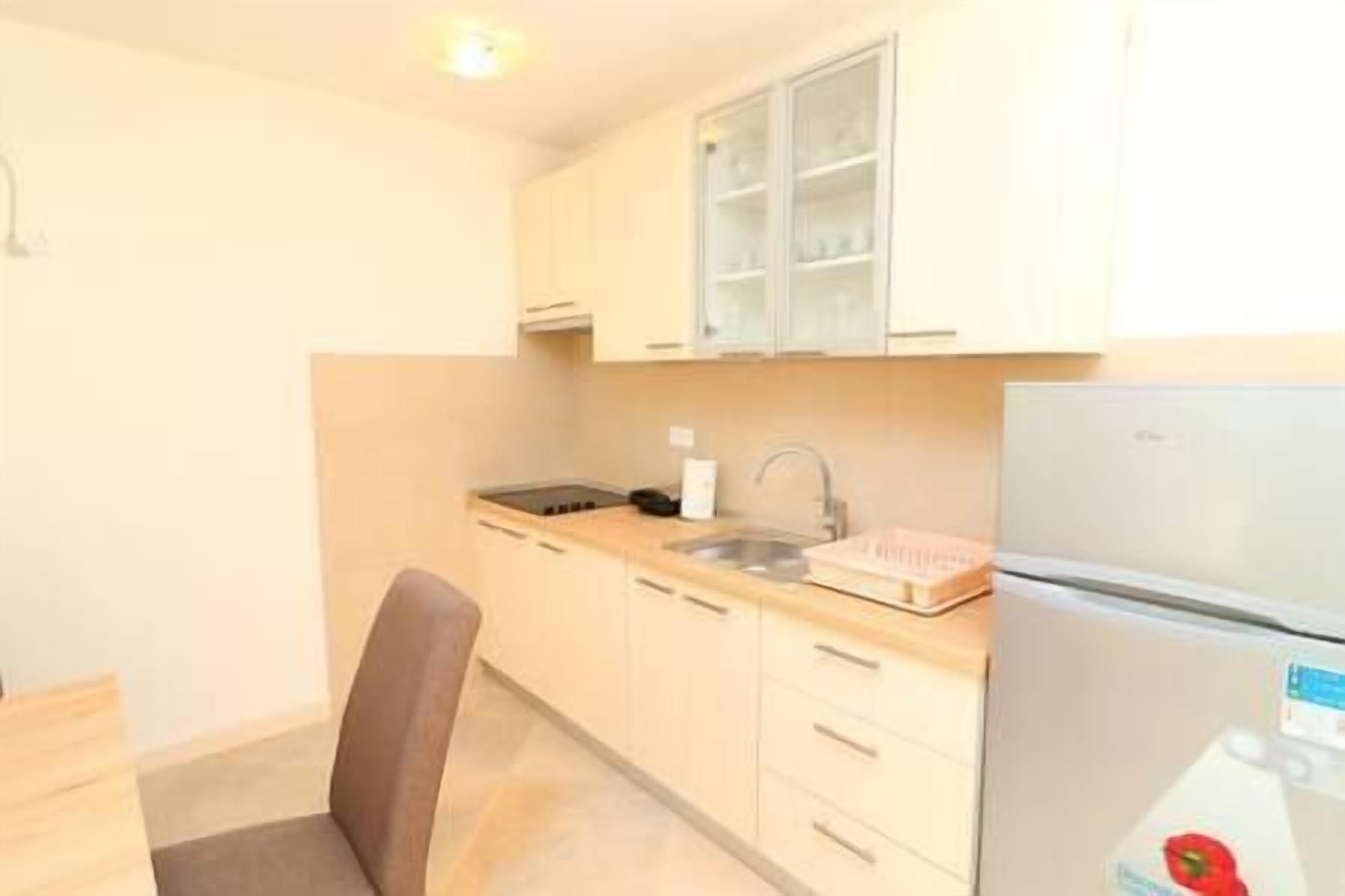 A small kitchen with white cabinets, a sink, and a refrigerator.