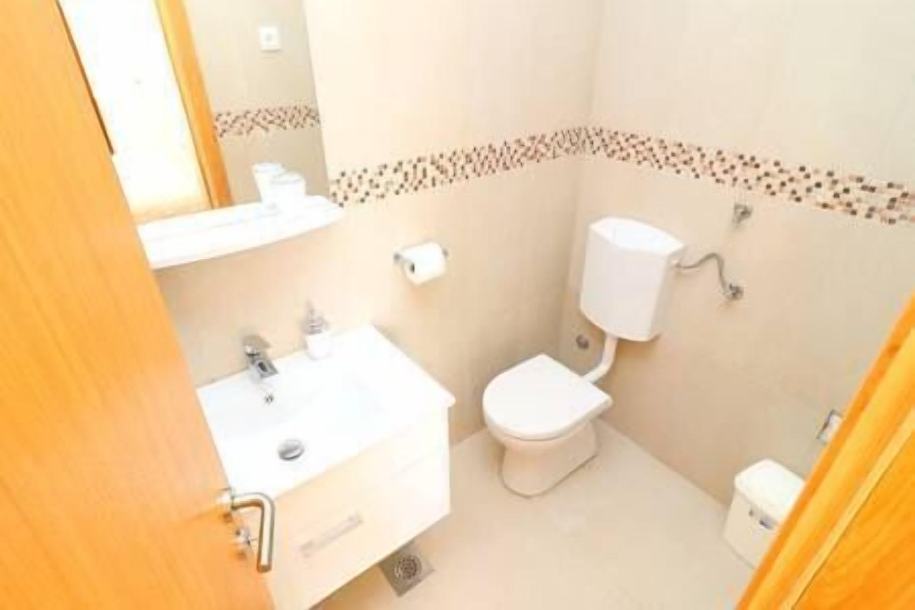 A small bathroom with a sink, toilet, and mirror.