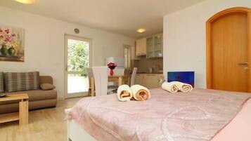 Un dormitorio con una cama, una puerta de madera, un cuadro y vistas a una cocina y comedor.