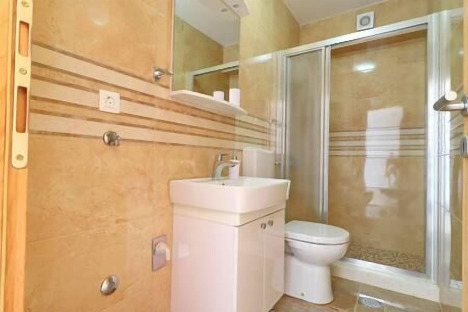 A bathroom with a white sink, a toilet, and a glass shower enclosure.