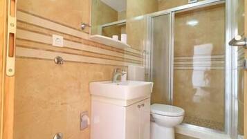 A bathroom with a white sink, a toilet, and a glass shower enclosure.