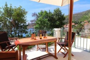 Una mesa y sillas de madera en un balcón con vistas a árboles y una masa de agua.