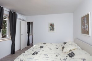 Un dormitorio con cama, puerta y ventana con cortinas.