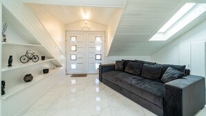 A modern interior with a white wooden ceiling, a black leather sofa, and a white door with windows. - Apartment Rea Zaton (Dubrovnik)