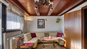 A cozy living room with a wooden ceiling, a sofa, a coffee table, and a radiator. - Forest Retreat Bonidesa - Terrace & Jacuzzi (Ljubno)