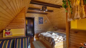 A cozy attic bedroom with wooden walls, a sloped ceiling, a bed with a checkered blanket, a small table, and a hanging macrame decoration. - Forest Retreat Bonidesa - Terrace & Jacuzzi (Ljubno)