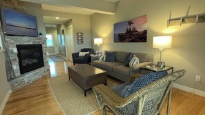 A living room with a fireplace, a sofa, a wicker chair, and a lamp. - Remodeled Downtown Condo Across the Street from Jo (La Pointe)