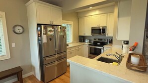 A modern kitchen with stainless steel appliances, white cabinetry, and a central island with a sink. - Remodeled Downtown Condo Across the Street from Jo (La Pointe)