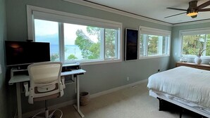 A bedroom with a bed, a desk with a chair, and three windows. - Remodeled Downtown Condo Across the Street from Jo (La Pointe)