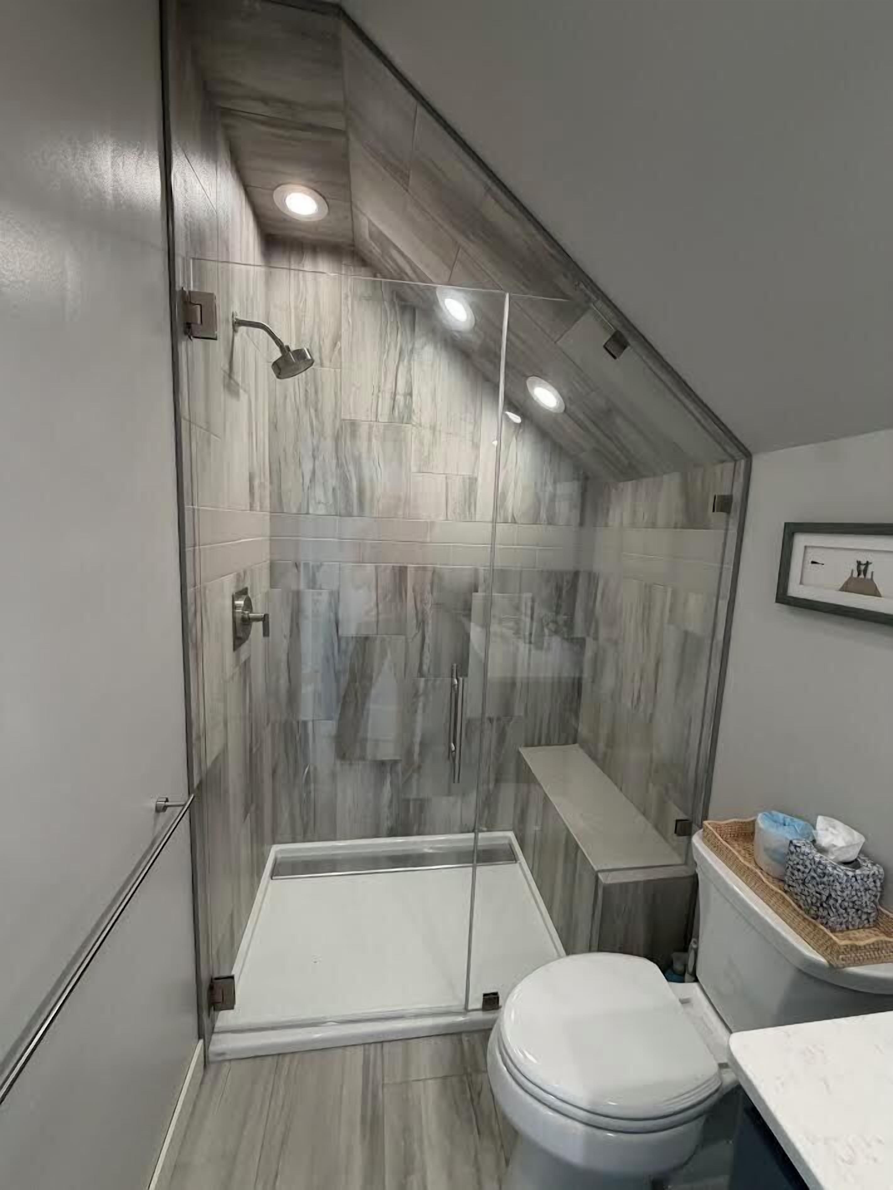 Un baño moderno con ducha envuelta en vidrio, inodoro y tocador con lavabo.