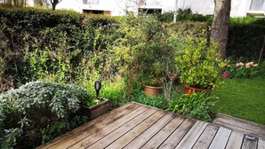 Une terrasse en bois agrémentée de plantes en pot et d’une haie en arrière-plan.