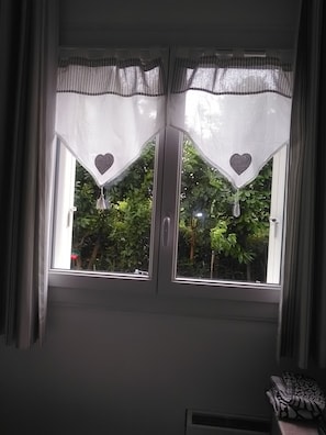 Ein Fenster mit zwei weißen Vorhängen, verziert mit herzförmigen Ausschnitten und Bändern.