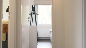 A hallway with a radiator, a window, and a ladder leaning against the wall.