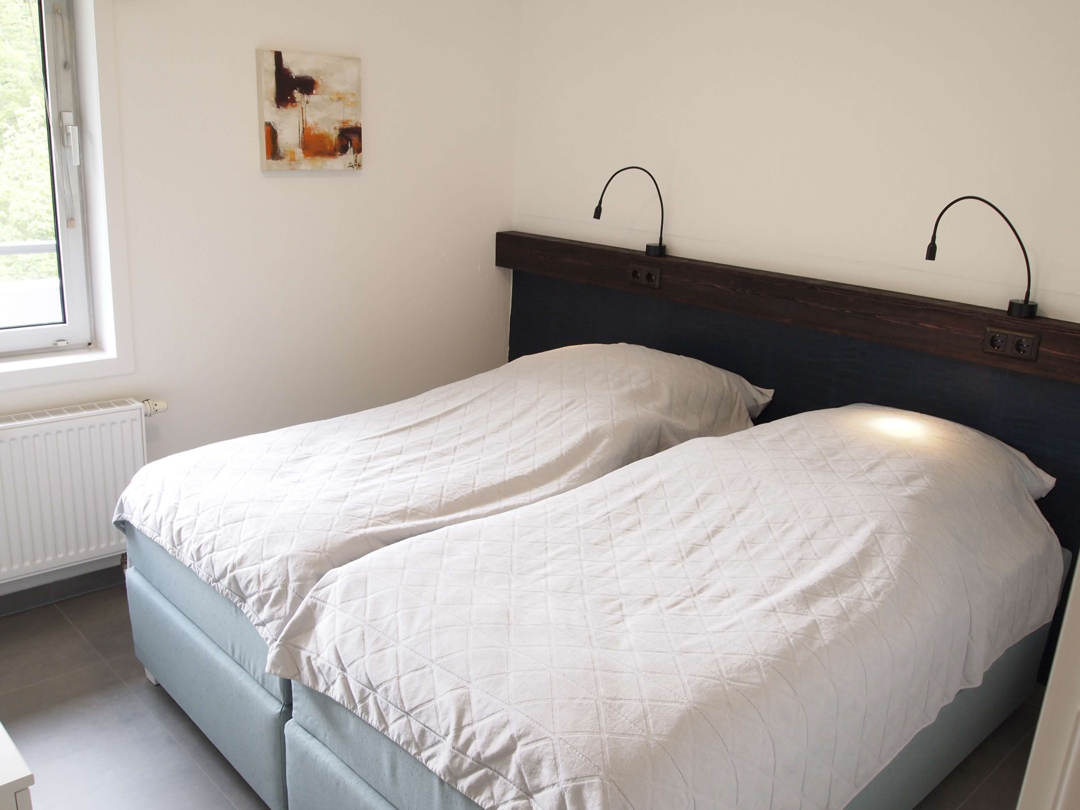 Una cama doble con un edredón blanco acolchado, un cabecero de madera y dos lámparas de noche.
