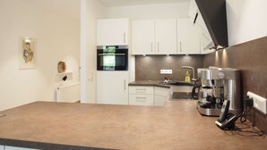 A modern kitchen with white cabinets, a built-in oven, a coffee machine, and a telephone.