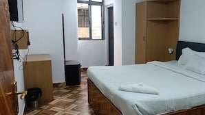 Ένα υπνοδωμάτιο με ένα κρεβάτι, μια ξύλινη ντουλάπα και ένα μικρό τραπέζι.