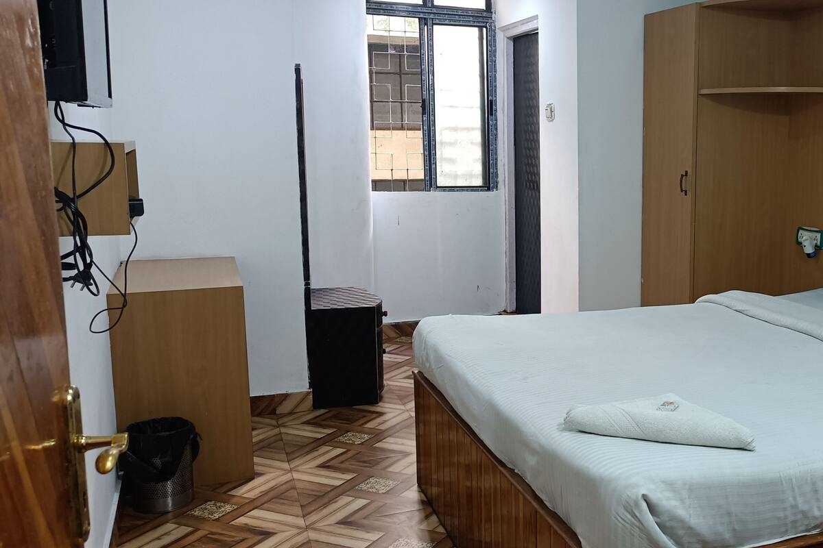 A bedroom with a bed, wooden wardrobe, and a small table.