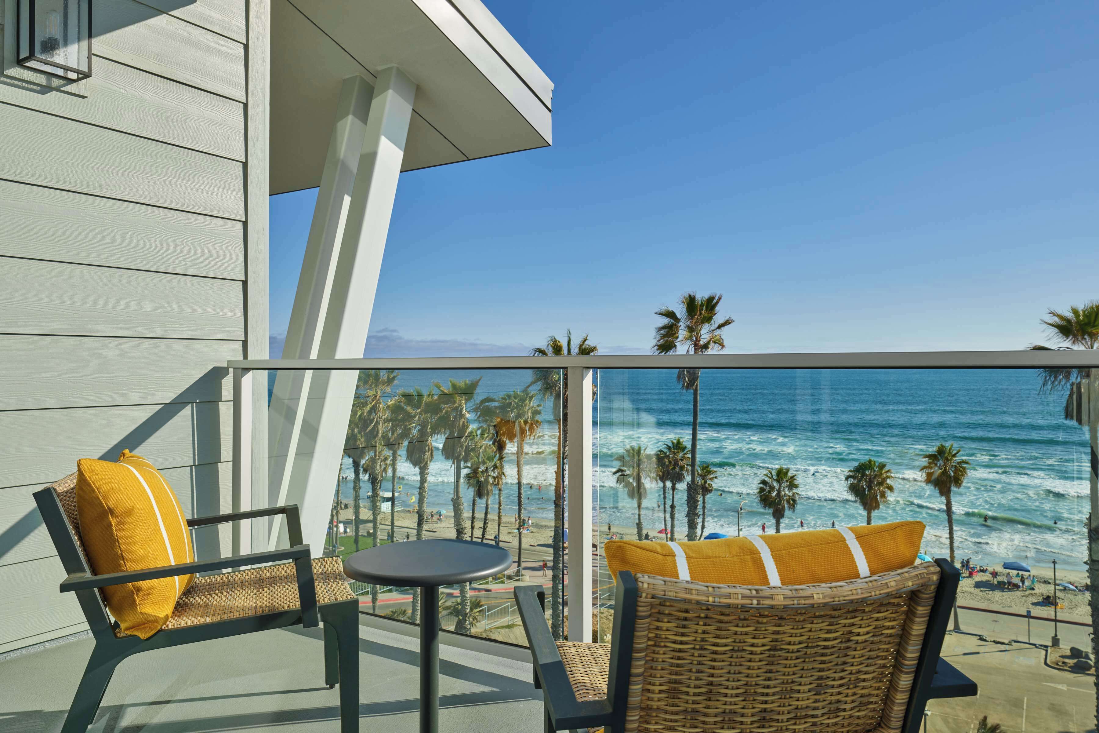 A balcony with wicker furniture and a view of the beach.