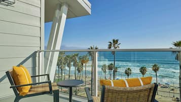A balcony with wicker furniture and a view of the beach.