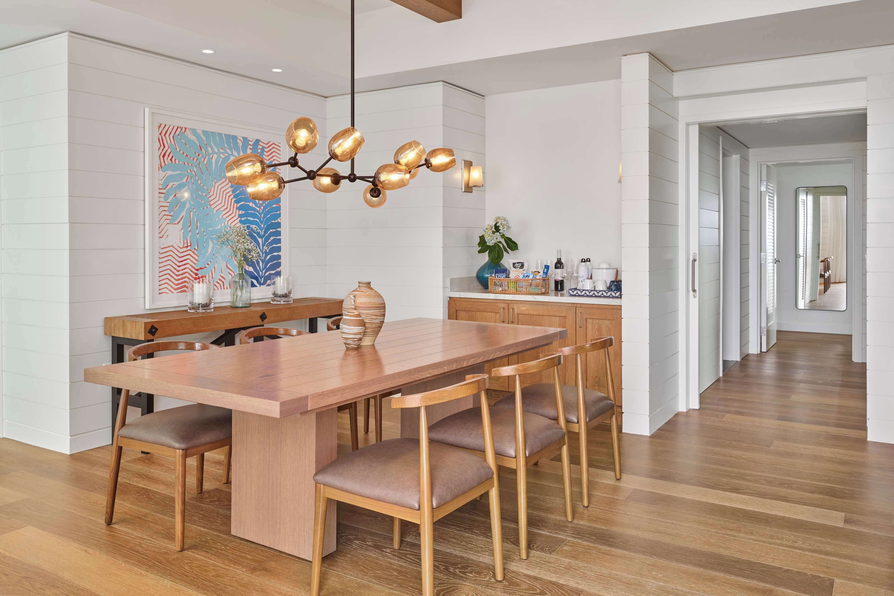 A modern kitchen with a wooden dining table, chairs, and a chandelier.
