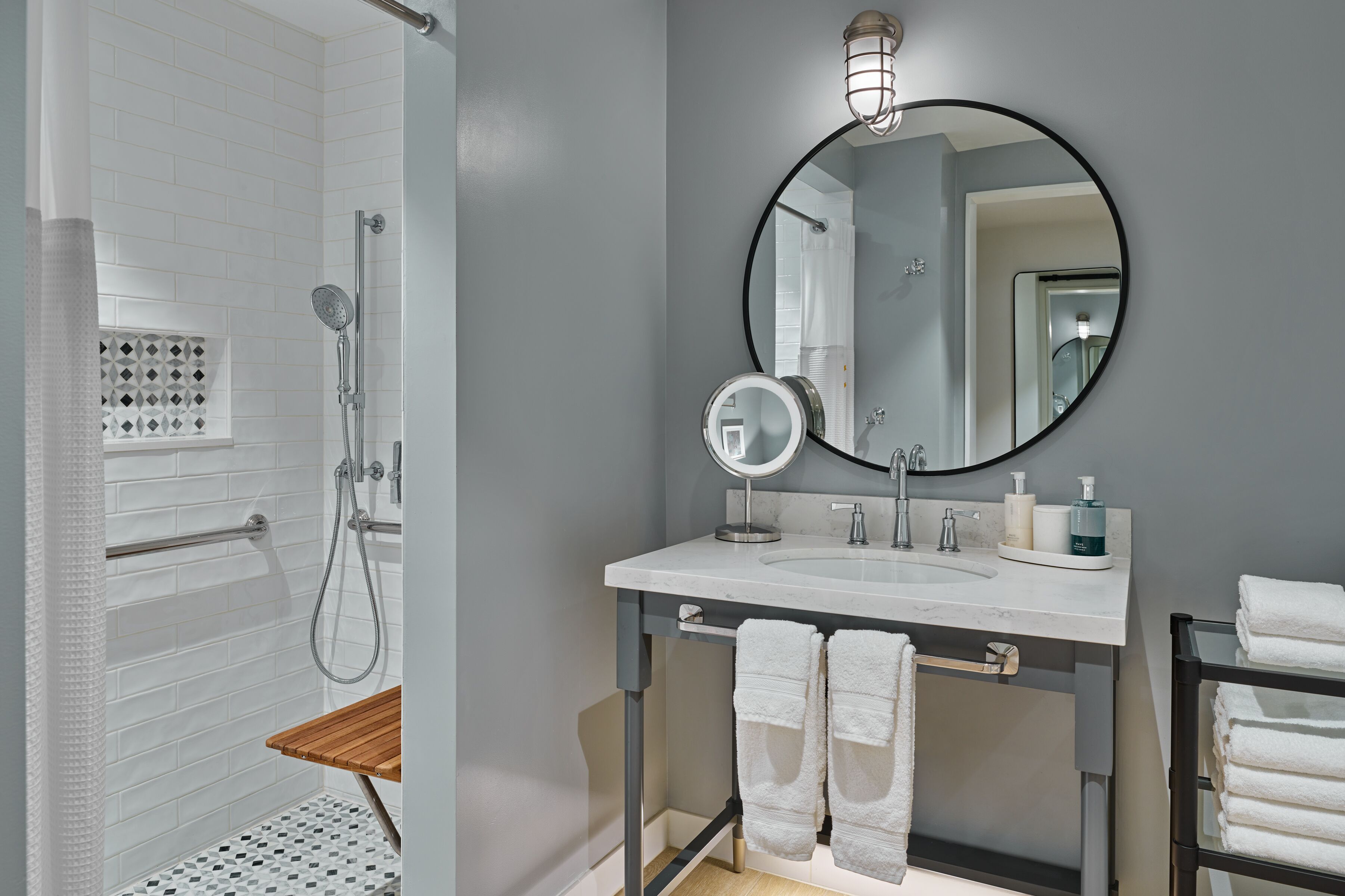 A modern bathroom with a shower, a sink with a mirror, and a towel rack.