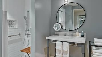 A modern bathroom with a shower, a sink with a mirror, and a towel rack.