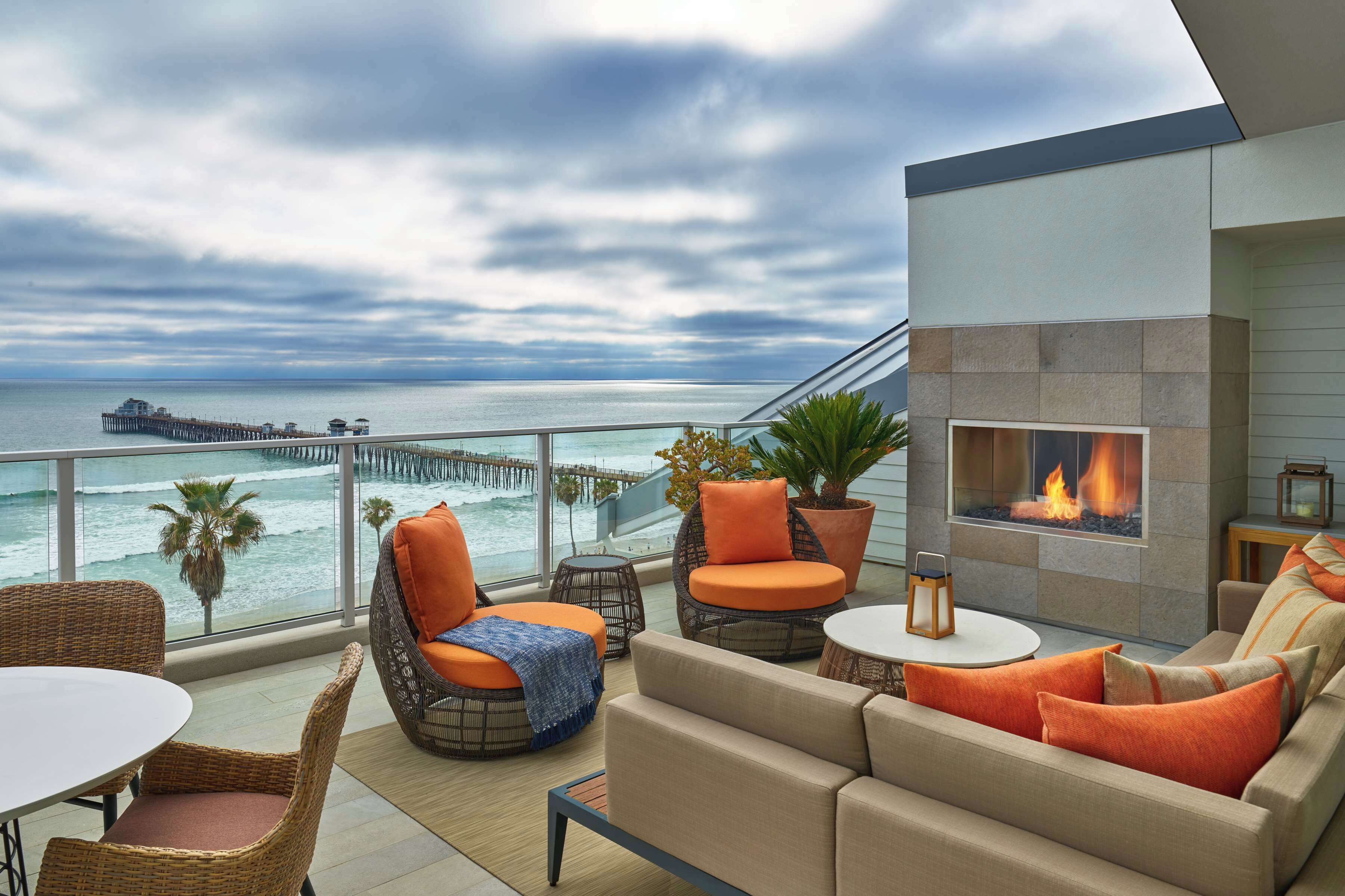 A balcony with wicker furniture, a sofa, and a fireplace.