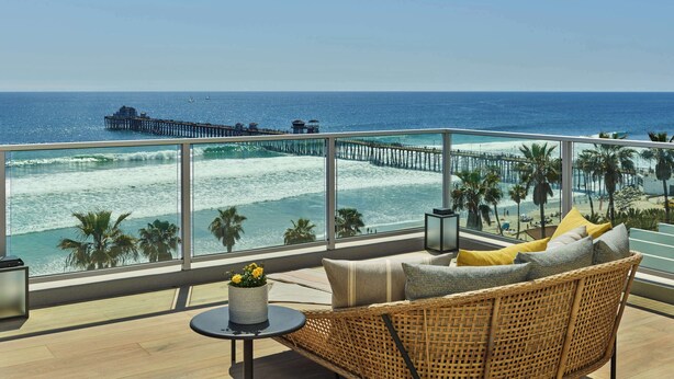 A balcony with a view of the ocean, a wooden chair, and a small table with flowers. - The Seabird Ocean Resort & Spa, Part of Destination Hotel by Hyatt (Oceanside)