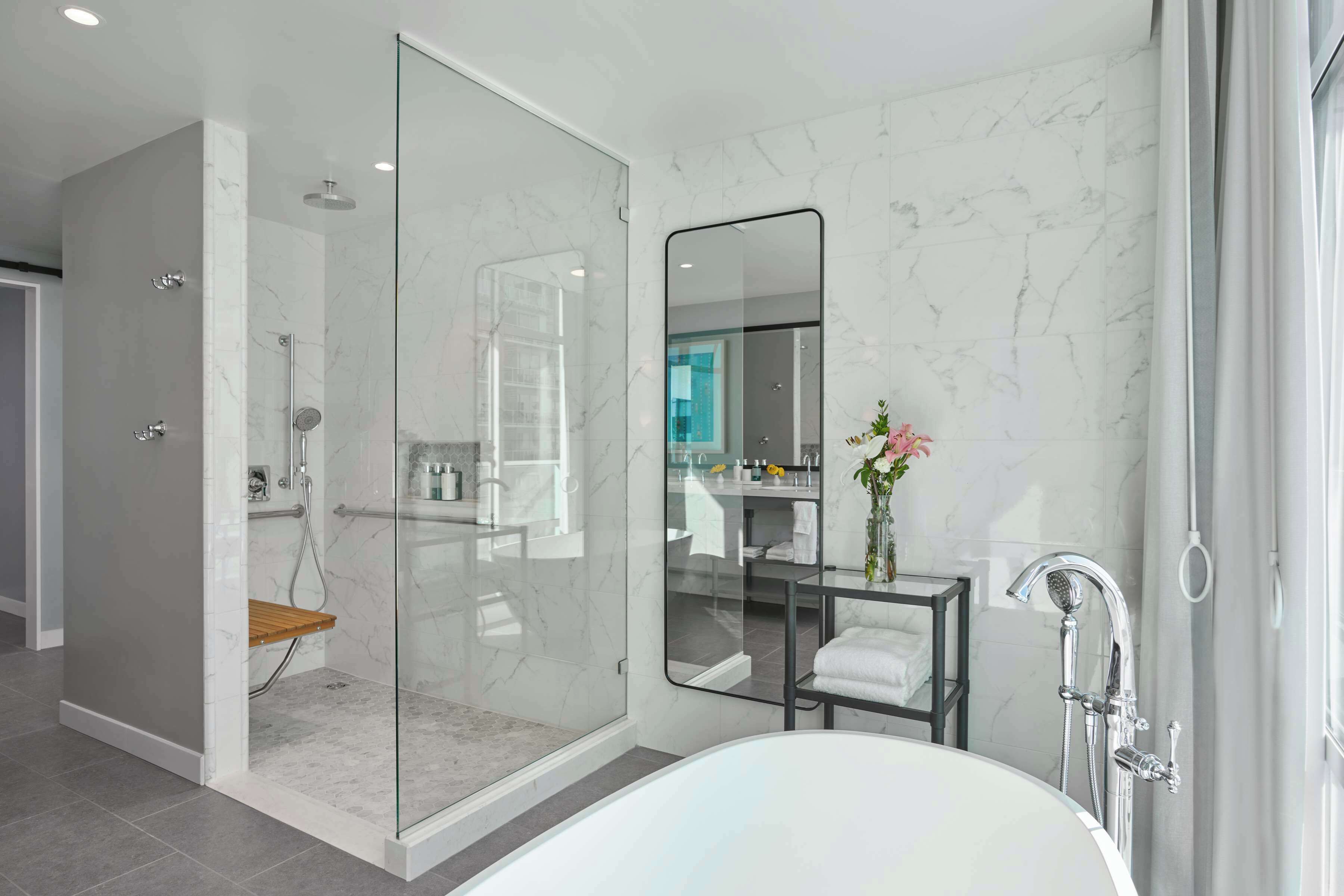 A modern bathroom with a glass-enclosed shower, a freestanding bathtub, and a vanity with a mirror.