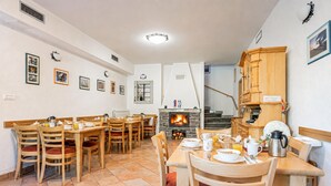 A dining area with wooden tables and chairs, a fireplace, and framed pictures on the walls.