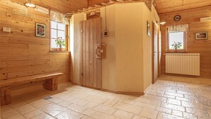 A wooden interior with a bench, a door, and a window with a plant.