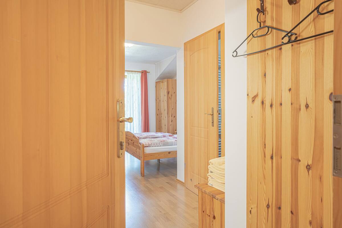 A wooden room with a bed, wardrobe, and a hanging coat rack.