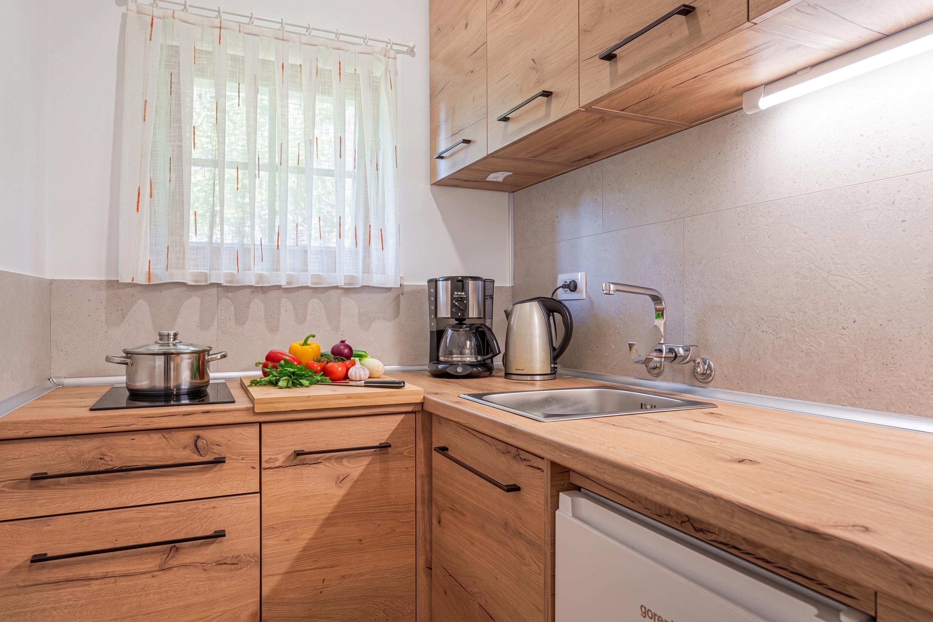 A modern kitchen with wooden cabinets, a built-in dishwasher, a coffee maker, and fresh vegetables on the counter.