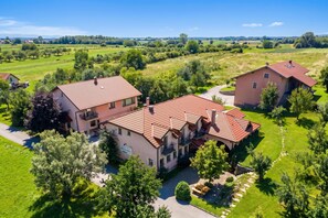 A large, two-story house with a red-tiled roof, surrounded by lush greenery and a clear sky. - Pivka Na Meji Resort (Pivka)