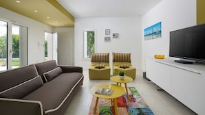 A modern living room with a sofa, two armchairs, a TV, and a small table. - Villa Deborah (Raša)