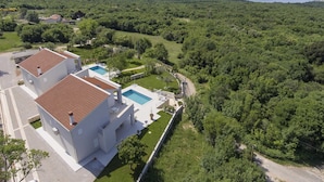 A modern villa with a swimming pool, surrounded by lush greenery and a view of the sea. - Villa Deborah (Raša)