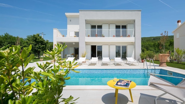 A two-story modern building with a pool, outdoor seating, and a balcony with potted plants. - Villa Deborah (Raša)